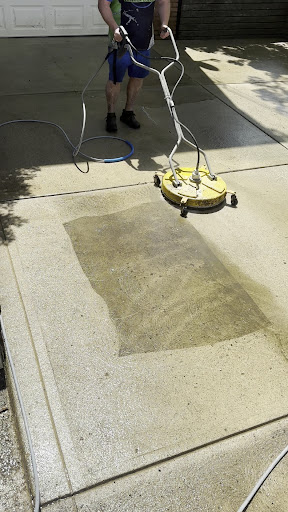 Sam from Mr. Lucky's Exterior Cleaning pressure washing a residential driveway with a surface cleaner